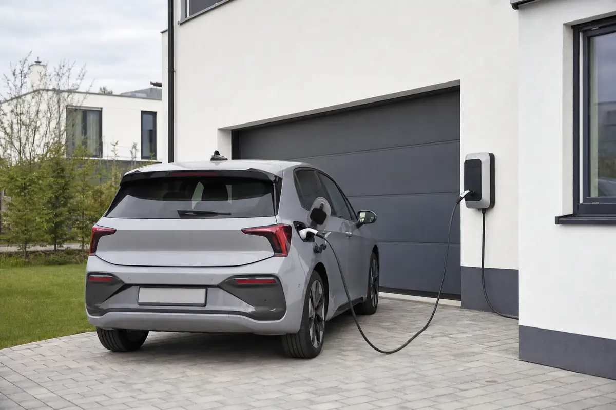 Elektroauto lädt an einer Wallbox neben der Garage (Symbolbild, mit KI erstellt)